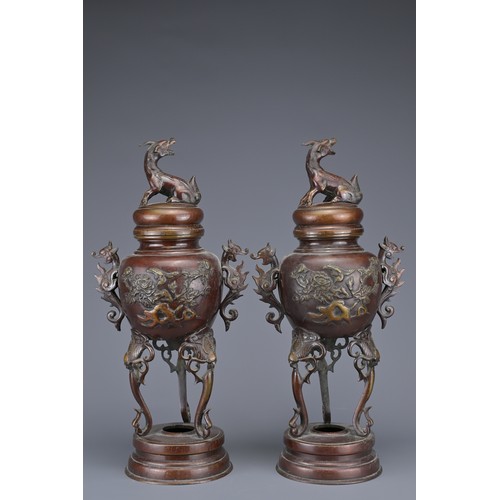 62 - A PAIR OF JAPANESE BRONZE LIDDED URNS. Each with ornate legs and dragon form handles with raised flo... 