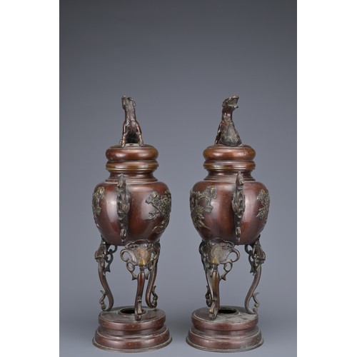 62 - A PAIR OF JAPANESE BRONZE LIDDED URNS. Each with ornate legs and dragon form handles with raised flo... 