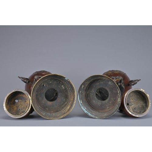 62 - A PAIR OF JAPANESE BRONZE LIDDED URNS. Each with ornate legs and dragon form handles with raised flo... 