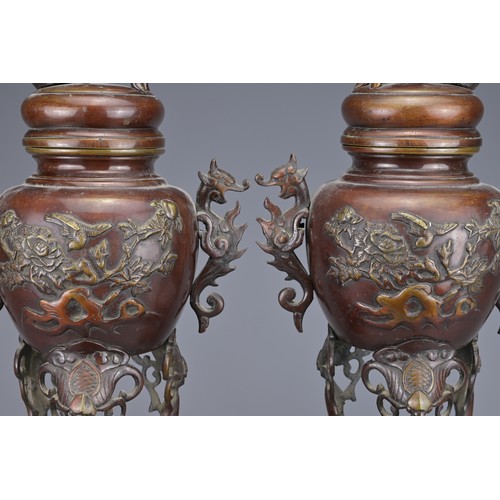 62 - A PAIR OF JAPANESE BRONZE LIDDED URNS. Each with ornate legs and dragon form handles with raised flo... 