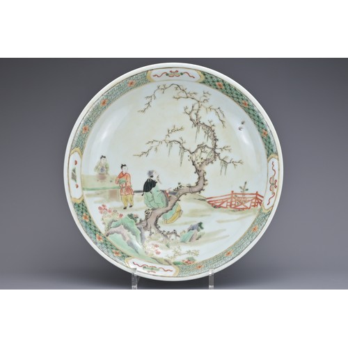 68 - A CHINESE FAMILLE VERTE PORCELAIN DISH. Depicting a garden scene with figure sat on a tree playing t... 