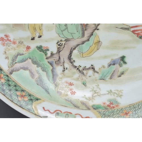 68 - A CHINESE FAMILLE VERTE PORCELAIN DISH. Depicting a garden scene with figure sat on a tree playing t... 