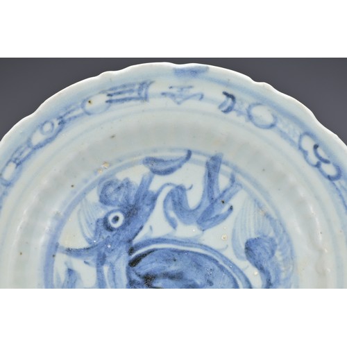 74 - A CHINESE BLUE AND WHITE PORCELAIN DISH, MING DYNASTY. Barbed rim and ribbed body decorated with qil... 