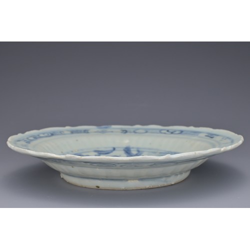 74 - A CHINESE BLUE AND WHITE PORCELAIN DISH, MING DYNASTY. Barbed rim and ribbed body decorated with qil... 