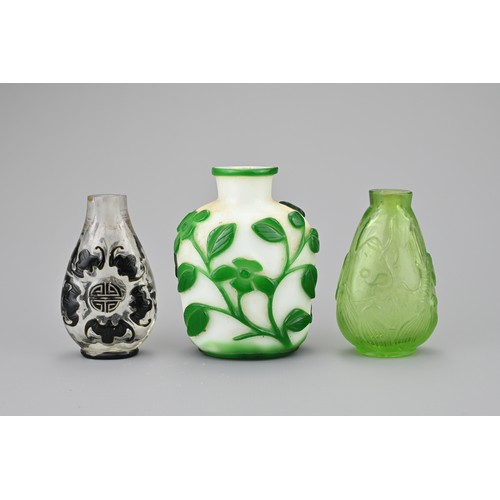 4 - THREE CHINESE GLASS SNUFF BOTTLES. Comprising a green-overlay white glass bottle with floral stems; ... 