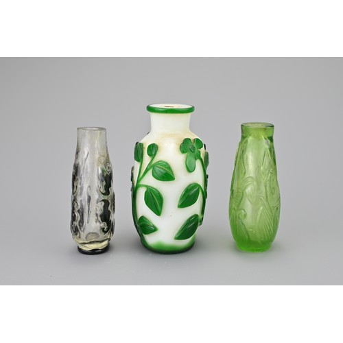 4 - THREE CHINESE GLASS SNUFF BOTTLES. Comprising a green-overlay white glass bottle with floral stems; ... 