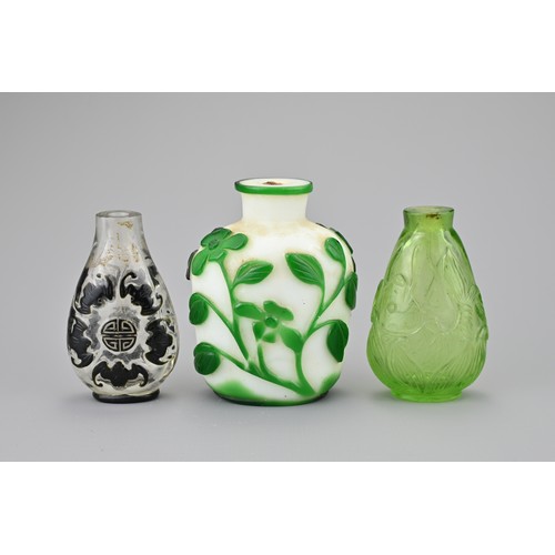 4 - THREE CHINESE GLASS SNUFF BOTTLES. Comprising a green-overlay white glass bottle with floral stems; ... 