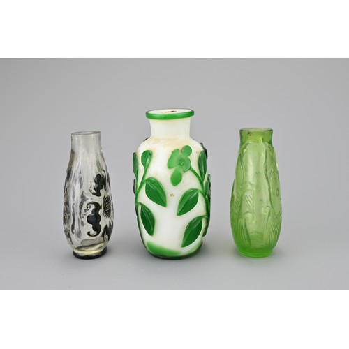 4 - THREE CHINESE GLASS SNUFF BOTTLES. Comprising a green-overlay white glass bottle with floral stems; ... 