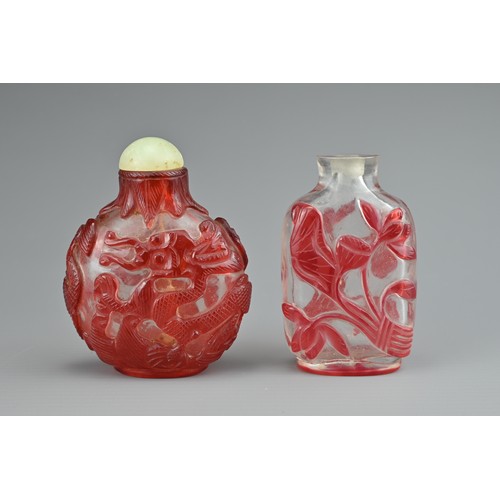 6 - TWO CHINESE GLASS SNUFF BOTTLES. To include a red-overlay glass bottle with dragons and green stone ... 