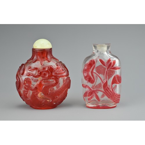 6 - TWO CHINESE GLASS SNUFF BOTTLES. To include a red-overlay glass bottle with dragons and green stone ... 