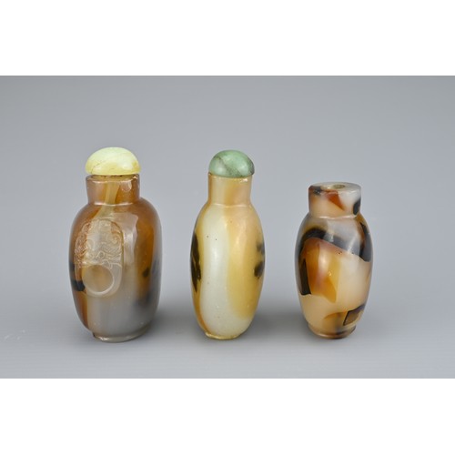 9 - THREE CHINESE SNUFF BOTTLES. Comprising two agate bottles with green stone stoppers, one with caved ... 