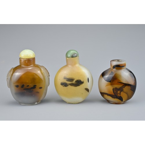 9 - THREE CHINESE SNUFF BOTTLES. Comprising two agate bottles with green stone stoppers, one with caved ... 