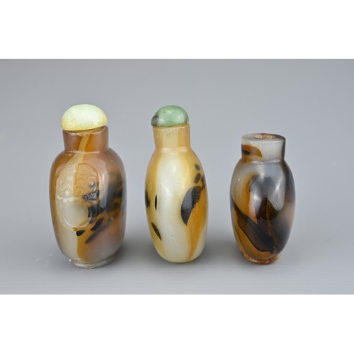 9 - THREE CHINESE SNUFF BOTTLES. Comprising two agate bottles with green stone stoppers, one with caved ... 