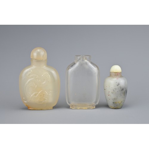 22 - THREE CHINESE SNUFF BOTTLES, QING DYNASTY. Comprising a flattened clear rock crystal bottle; a carve... 