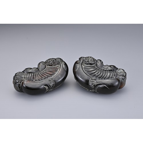 57 - A PAIR OF CHINESE CARVED HORN FOO DOGS, QING DYNASTY. Each recumbent holding a 'pierced' ball. Each ... 