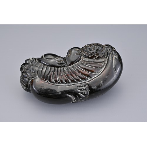 57 - A PAIR OF CHINESE CARVED HORN FOO DOGS, QING DYNASTY. Each recumbent holding a 'pierced' ball. Each ... 