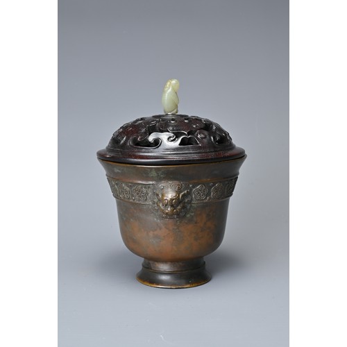 44 - A CHINESE BRONZE CENSER AND COVER. In the form of a cup with lion mask handles and band of floral de... 