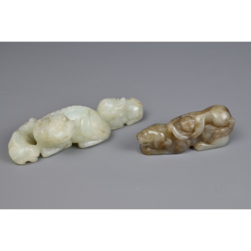 89 - TWO CHINESE JADE CARVINGS. A pale celadon jade carving of a lion group together with a mottled celad... 