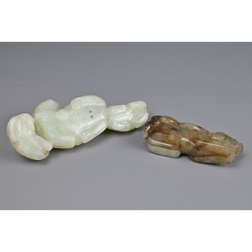 89 - TWO CHINESE JADE CARVINGS. A pale celadon jade carving of a lion group together with a mottled celad... 