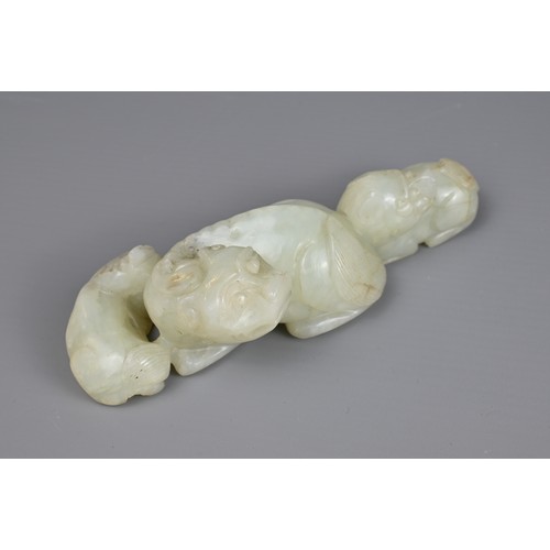 89 - TWO CHINESE JADE CARVINGS. A pale celadon jade carving of a lion group together with a mottled celad... 