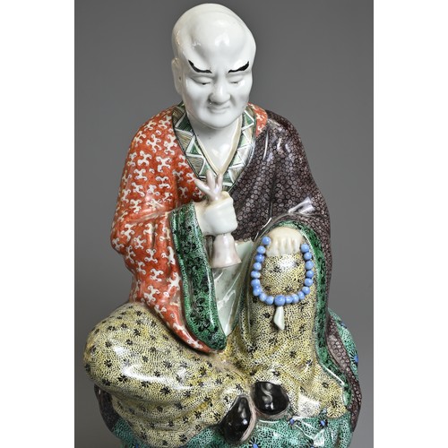 3 - A CHINESE POLYCHROME DECORATED PORCELAIN FIGURE OF LUOHAN, EARLY 20TH CENTURY. The male figure seate... 