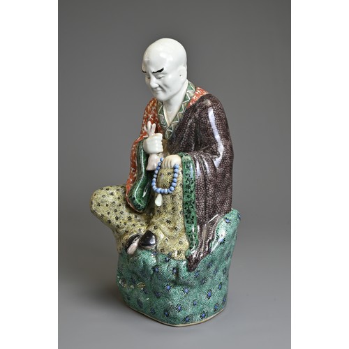 3 - A CHINESE POLYCHROME DECORATED PORCELAIN FIGURE OF LUOHAN, EARLY 20TH CENTURY. The male figure seate... 