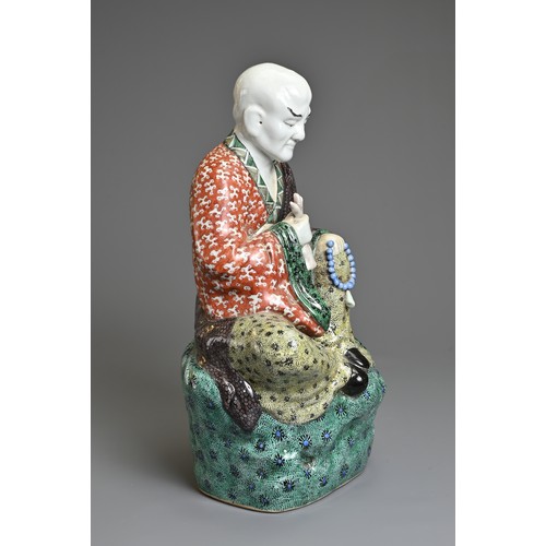 3 - A CHINESE POLYCHROME DECORATED PORCELAIN FIGURE OF LUOHAN, EARLY 20TH CENTURY. The male figure seate... 