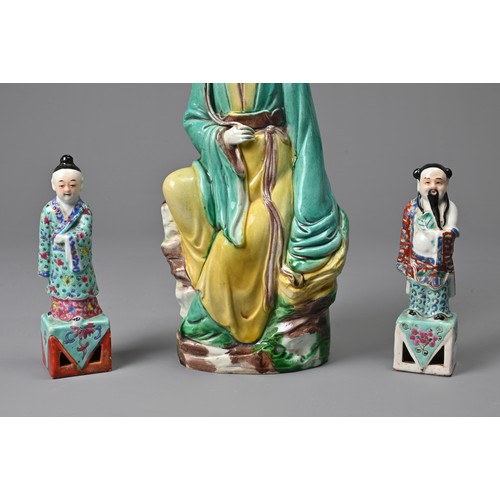 32 - THREE CHINESE GLAZED PORCELAIN FIGURES, 20TH CENTURY. A figure of Guanyin holding a lotus spray with... 