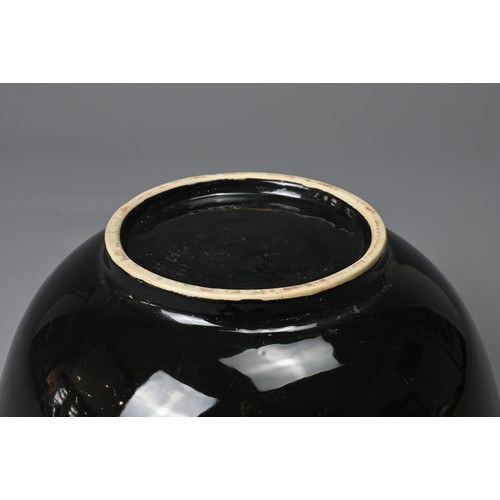 61 - A LARGE CHINESE BLACK GLAZED PORCELAIN BOWL, 20TH CENTURY. Heavily potted round bowl covered in a bl... 