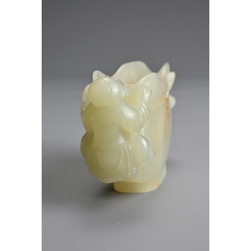 26 - A CHINESE CARVED PALE CELADON JADE CUP. Pale celadon colour with russet patches, featuring a boy han... 