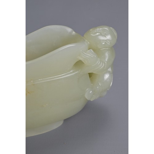 26 - A CHINESE CARVED PALE CELADON JADE CUP. Pale celadon colour with russet patches, featuring a boy han... 