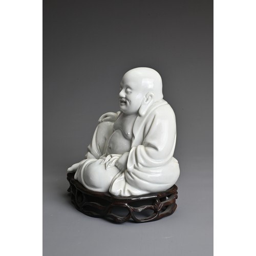 35 - A CHINESE BLANC DE CHINE FIGURE OF BUDAI, QING DYNASTY. The figure seated dressed in robes open at t... 