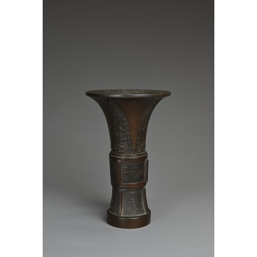 47 - A CHINESE BRONZE GU SHAPED VASE, QING DYNASTY. Archaic decoration with Taotie masks and flanges to t... 