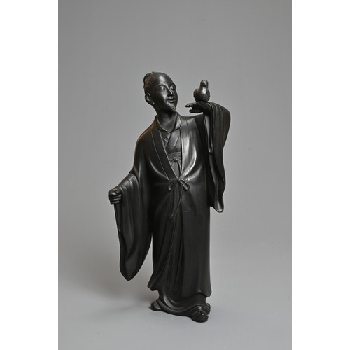 299 - A 20TH CENTURY JAPANESE BRONZE OF A FIGURE OF A SCHOLAR HOLDING ALOFT A BIRD. Cast standing in a lon... 