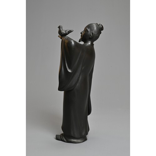 299 - A 20TH CENTURY JAPANESE BRONZE OF A FIGURE OF A SCHOLAR HOLDING ALOFT A BIRD. Cast standing in a lon... 