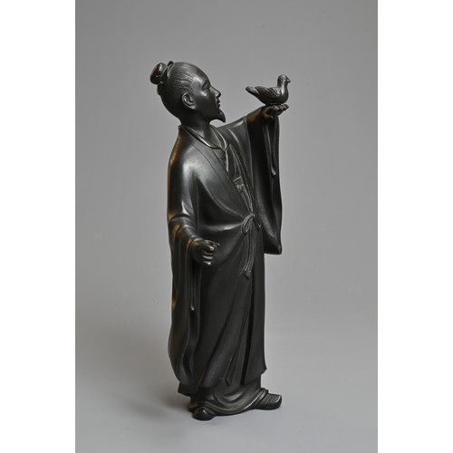 299 - A 20TH CENTURY JAPANESE BRONZE OF A FIGURE OF A SCHOLAR HOLDING ALOFT A BIRD. Cast standing in a lon... 