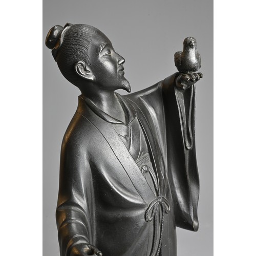 299 - A 20TH CENTURY JAPANESE BRONZE OF A FIGURE OF A SCHOLAR HOLDING ALOFT A BIRD. Cast standing in a lon... 