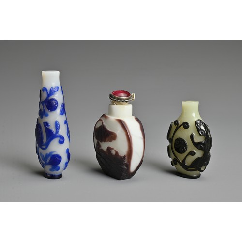 6 - THREE CHINESE GLASS OVERLAY SNUFF BOTTLES. To include  a black overlay bottle with chilong and yin y... 