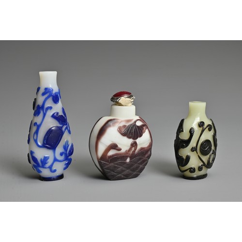 6 - THREE CHINESE GLASS OVERLAY SNUFF BOTTLES. To include  a black overlay bottle with chilong and yin y... 