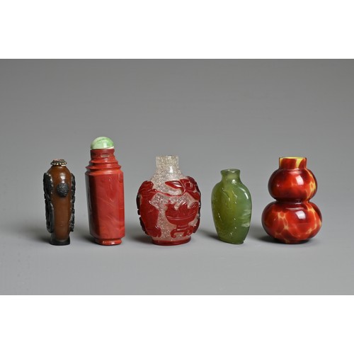 8 - A GROUP OF FIVE CHINESE GLASS SNUFF BOTTLES. To include a red overlay clear glass bottle with treasu... 