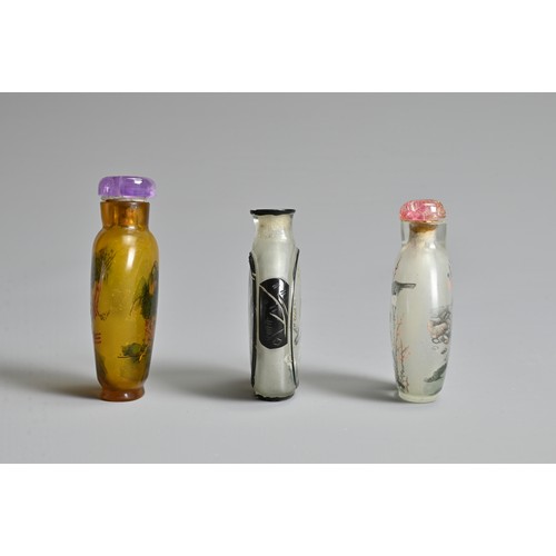 14 - THREE CHINESE GLASS SNUFF BOTTLES. To include an inside painted bottle with black overlay, decorated... 