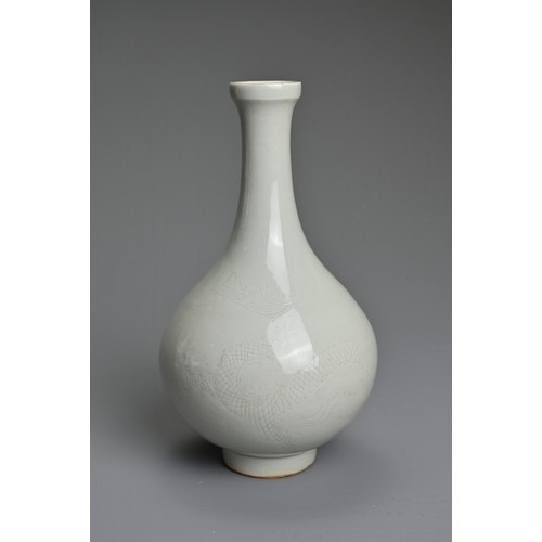 83 - A CHINESE WHITE GLAZED BOTTLE VASE. Of pear shape on raised foot incised with figure of a dragon. Wi... 