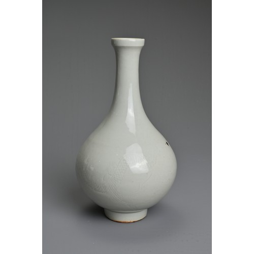 83 - A CHINESE WHITE GLAZED BOTTLE VASE. Of pear shape on raised foot incised with figure of a dragon. Wi... 