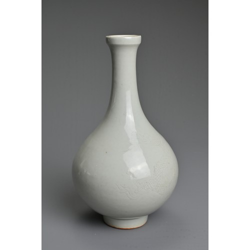 83 - A CHINESE WHITE GLAZED BOTTLE VASE. Of pear shape on raised foot incised with figure of a dragon. Wi... 