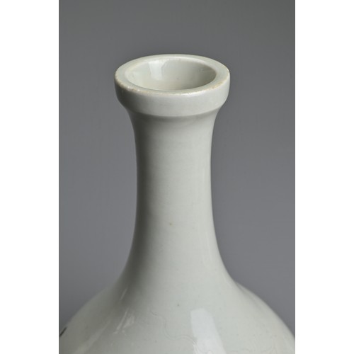 83 - A CHINESE WHITE GLAZED BOTTLE VASE. Of pear shape on raised foot incised with figure of a dragon. Wi... 