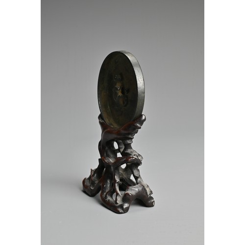 163 - A CHINESE BRONZE MIRROR ON WOODEN STAND, TANG DYNASTY (618–907). Circular form with animal form fini... 