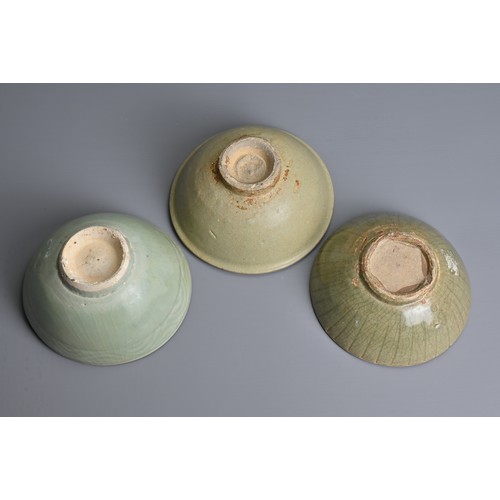 144 - THREE CHINESE CELADON GLAZED BOWLS, YUAN / MING DYNASTY. Each thickly potted with varying designs. 1... 