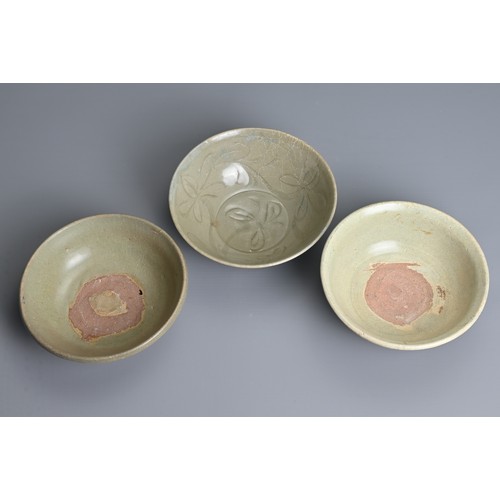 143 - THREE CHINESE CELADON GLAZED BOWLS, YUAN / MING DYNASTY. Each of varying sizes and designs. The larg... 