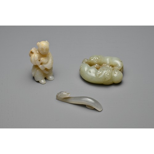 72 - THREE CHINESE CARVED JADE ITEMS. To include a celadon lion group; A small grey dragon head belt hook... 