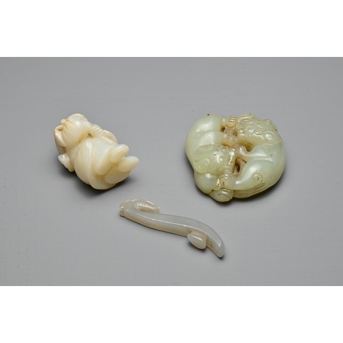 72 - THREE CHINESE CARVED JADE ITEMS. To include a celadon lion group; A small grey dragon head belt hook... 